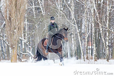 Young woman galloping on bay horse on winter field Stock Photo