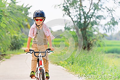 Young rider kid in helmet and sunglasses riding bicycle Stock Photo