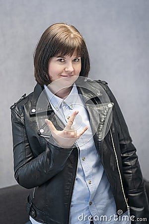 Young rock Girl in leather jacket. Punk is not dead. Girl making horn sign hand gesture. Cheerful woman rock lover Stock Photo