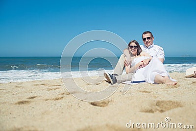 Young romantic couple sitting on the beach Stock Photo