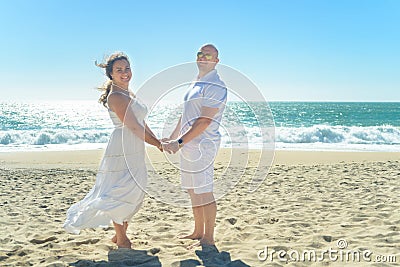 Young romantic couple standing on the beach holding hands Stock Photo