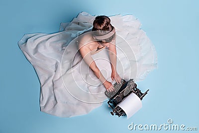 young romantic woman is an author at a typewriter, sitting on the floor in a fluffy white skirt Stock Photo