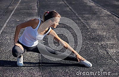 Young runner fit woman streching before exercises outdoors. Athletic female strech after workout outside. Sport and Stock Photo