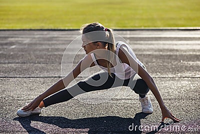 Young runner fit woman streching before exercises outdoors. Athletic female strech after workout outside. Sport and Stock Photo