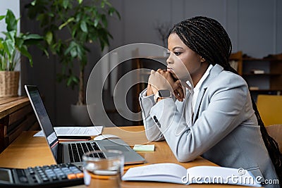 Frustrated african businesswoman looking thoughtfully at open laptop and trying to focus on work Stock Photo