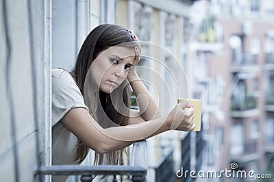 Young sad beautiful woman suffering depression looking worried and wasted on home balcony Stock Photo