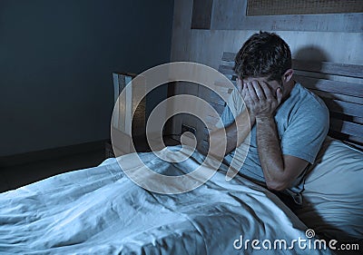 Young sad and depressed sleepless man lying on bed worried and thoughtful at home bedroom suffering depression problem feeling Stock Photo