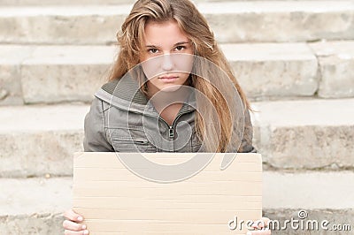 Young sad girl outdoor with blank cardboard sign. Stock Photo