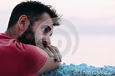 Young sad man by the sea looking at water Stock Photo