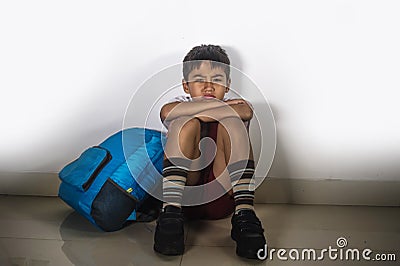 Young sad scared kid 8 years old in school uniform and backpack sitting alone crying depressed and frightened suffering abuse prob Stock Photo
