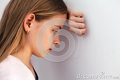 Young sad teenager girl propping her head against the wall Stock Photo