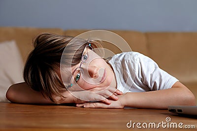 Young sad tired schoolboy, almost sleeps on desk Stock Photo