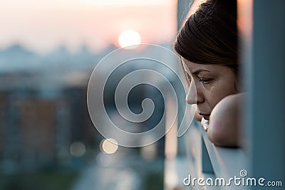 Young sad woman looking outside through balcony Stock Photo