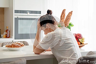 Young sad woman suffering in kitchen, Stressed housewife in kitchen Stock Photo