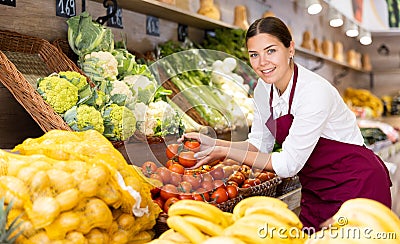 Young saleswoman offering tomatoes in eco products store Stock Photo