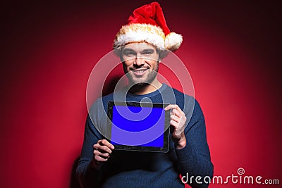 Young santa man holding a blue screen tablet pad computer Stock Photo