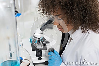 Young Scientist Looking Through Microscope In Laboratory, Mix Race Researcher Doing Research Experiments Stock Photo