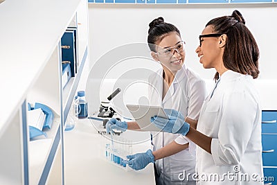 Young scientists using digital tablet while making experiment in chemical laboratory, scientists working together Stock Photo