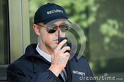 Young Security Guard Talking On Walkie-talkie Stock Photo