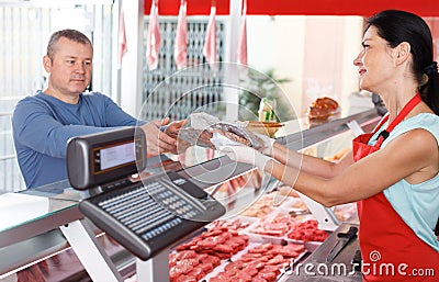 Young seller helping male choosing sausages Stock Photo