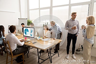 Young and senior employees doing different office activities in Stock Photo