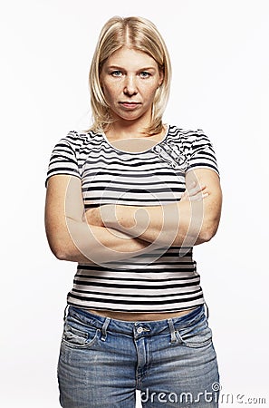 Young serious blonde woman in jeans crossed her arms over her chest. White background. Vertical Stock Photo