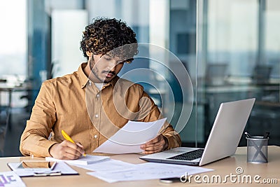 Young serious focused and thinking businessman paper work, successful hispanic man reviewing contract reports and Stock Photo