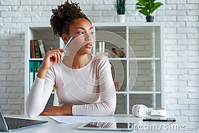 Young serious mulatto woman sits and thoughtfully looking sideways Stock Photo