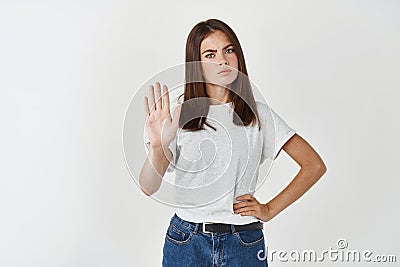 Young serious woman telling no, extend palm in stop sign and frowning disappointed, refuse or prohibit something Stock Photo