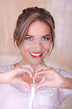 Young beautiful woman holding a menstruation cotton tampon with both hands and doing a heart sign with her hands Stock Photo