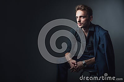 Young man in a classic suit sitting on a chair Stock Photo