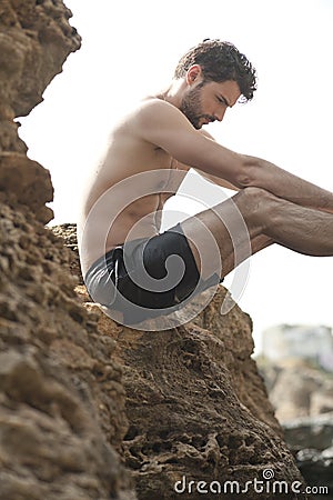 Young sexy man outdoor portrait sitting on a rock, topless Stock Photo