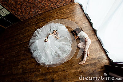 Young photographer is taking pictures the bride in the studio Stock Photo