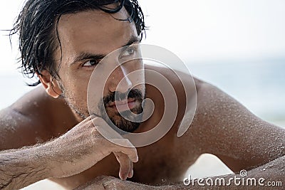 Young sexy stylish handsome latin man lies on a tropical beach, sand on tanned skin, sunbathing vacation concept Stock Photo