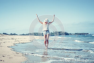 Young woman with white hat walking on white sand beach a tropical Bali island at sunny day. Ocean cost. Stock Photo