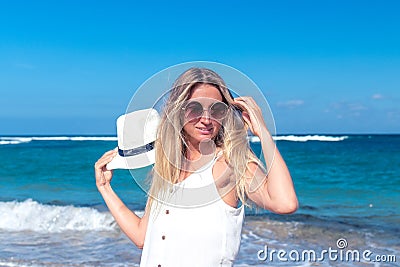 Young woman with white hat walking on white sand beach a tropical Bali island at sunny day. Ocean cost. Stock Photo