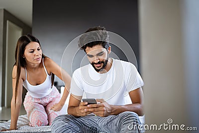 Young shocked wife caught husband on cheating snooping his messages with lover on smartphone Stock Photo
