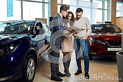 Young shop assistant explaing the features of a car Stock Photo