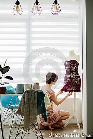 Young female clothing designer using dress dummy at cozy home interior, freelance lifestyle. Vertical shot Stock Photo
