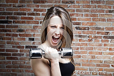 Young shouting fit woman lifting dumbbells Stock Photo