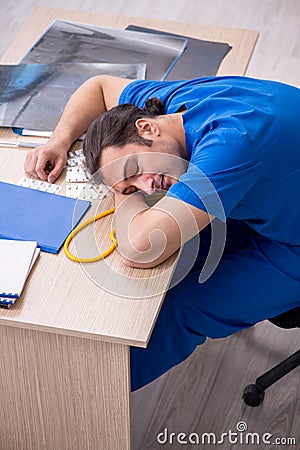 Young male sick doctor being unhappy after night shift Stock Photo