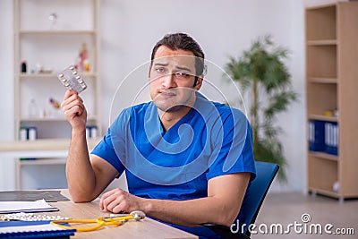 Young male sick doctor being unhappy after night shift Stock Photo