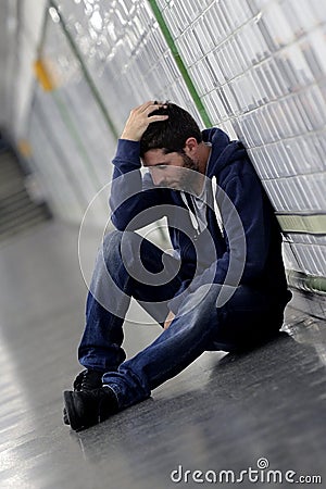 Young sick man lost suffering depression sitting on ground street subway tunnel Stock Photo