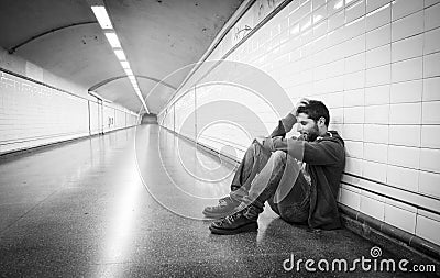 Young sick man lost suffering depression sitting on ground street subway tunnel Stock Photo