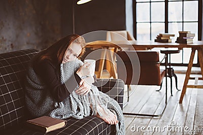 Young sick woman healing with hot drink at home on cozy couch Stock Photo