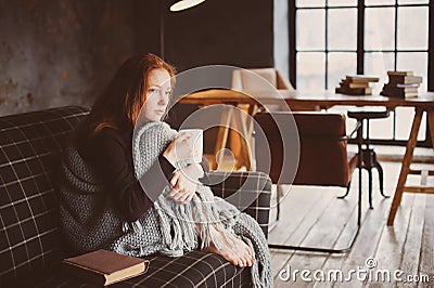 Young sick woman healing with hot drink at home on cozy couch Stock Photo