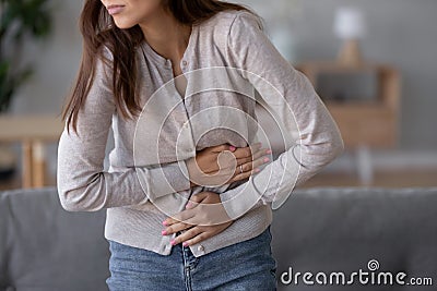 Young sick woman standing holding belly suffering from stomach pain Stock Photo