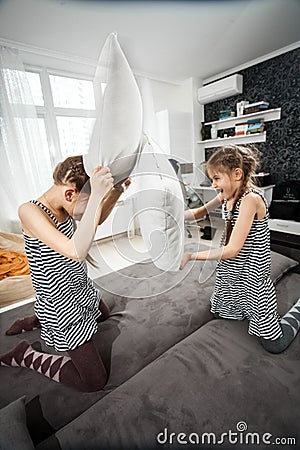 Young sisters pillow fighting on couch Stock Photo