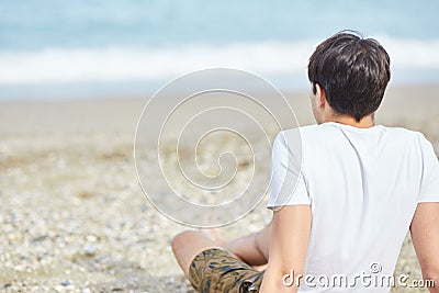 Young sitting beach looking at sea Stock Photo