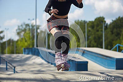 Young skater girl riding in a skatepark. Aggressive inline roller blader female skating in a outdoor concrete park Stock Photo
